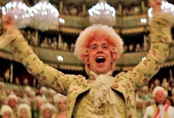 An ornate 18th century Viennese opera house interior lit by hundreds of candles, gilded balconies packed with aristocrats in powdered wigs, an orchestra in the pit below, warm amber light, dramatic theatrical atmosphere